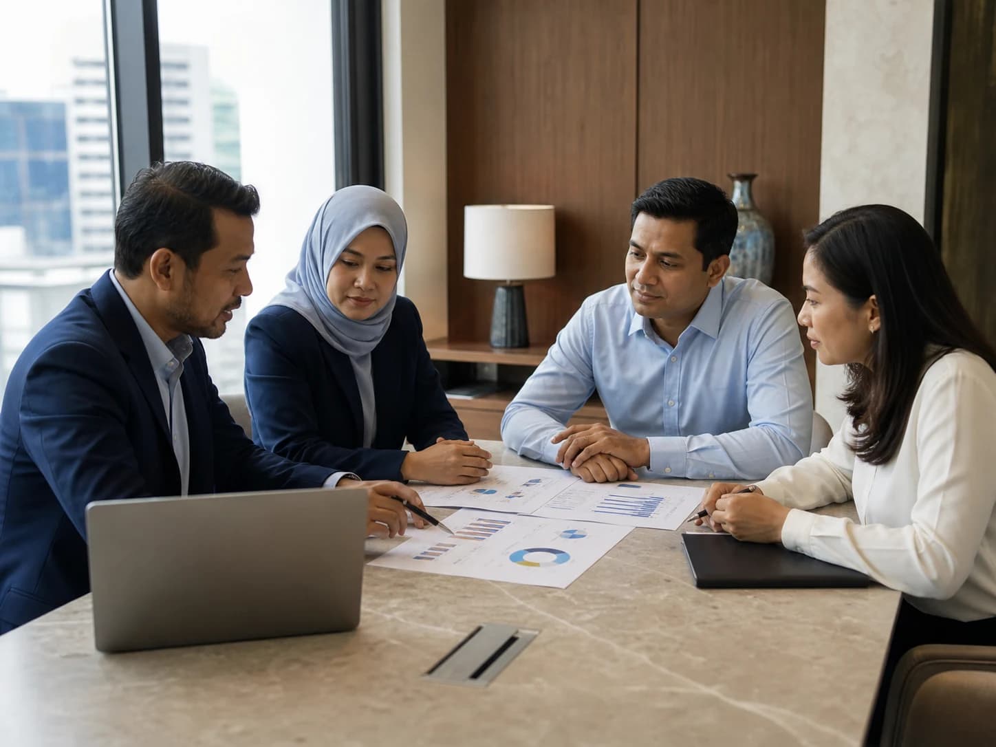 Malaysian professionals discussing financial documents in an advisory meeting